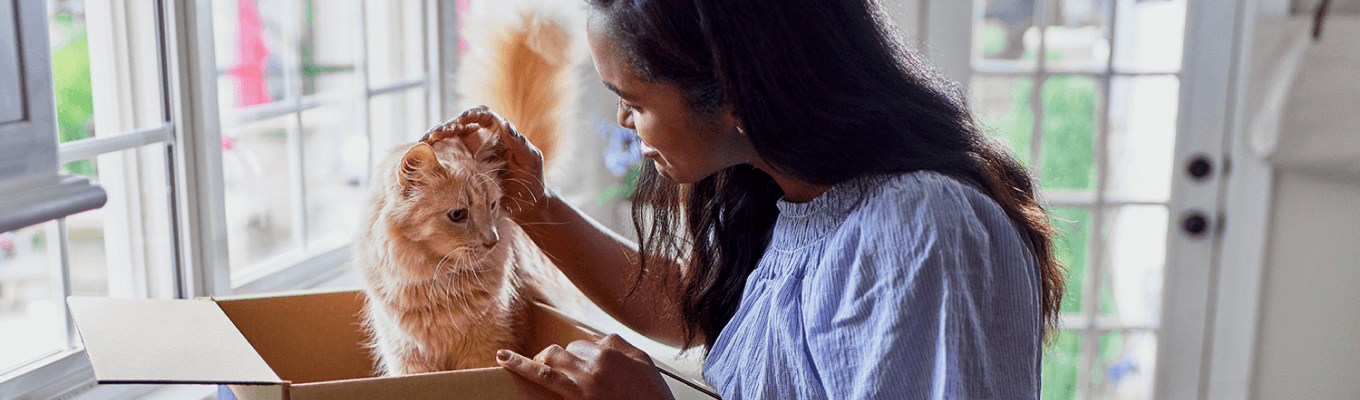 A pet owner and a cat sitting inside Hill's Pet food packaging